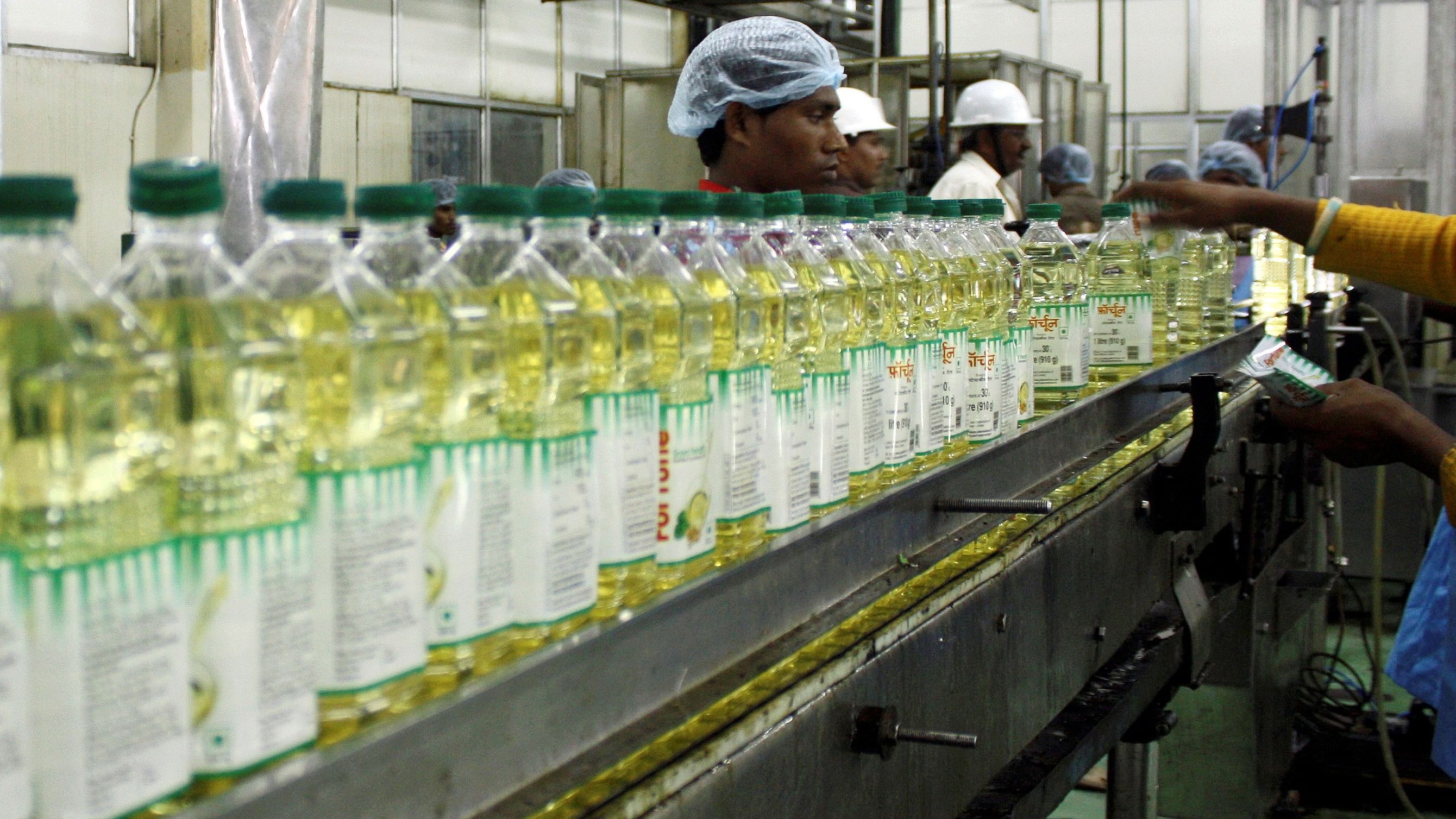 <div class="paragraphs"><p>Employees fill plastic bottles with edible oil at an oil refinery plant of Adani Wilmar Ltd.</p></div>