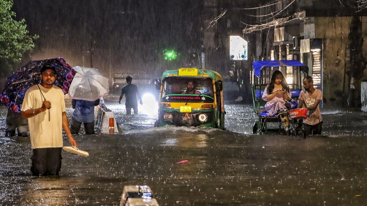 <div class="paragraphs"><p>People wade through a waterlogged road during rain at Jangpura area, in New Delhi.</p></div>