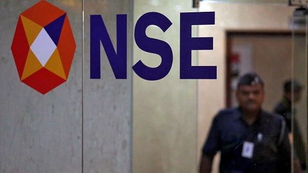 <div class="paragraphs"><p> A security guard walks past the logo of the National Stock Exchange inside its building in Mumbai.</p></div>