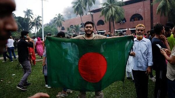 <div class="paragraphs"><p>People take pictures with the Bangladeshi flag, inside the Ganabhaban, the prime minister's residence, after the resignation of Prime Minister Sheikh Hasina in Dhaka, Bangladesh, August 5, 2024.</p></div>