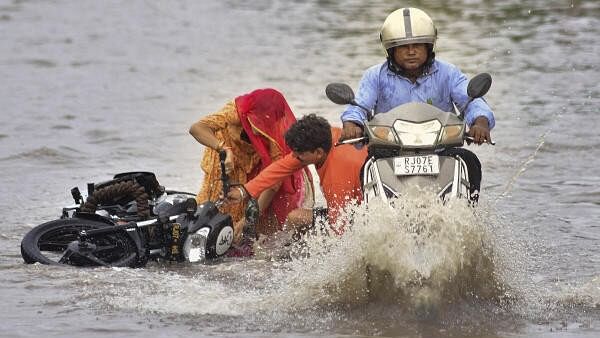 <div class="paragraphs"><p>Commuters on a two-wheeler lose balance on a waterlogged road after rain, in Bikaner.&nbsp;</p></div>