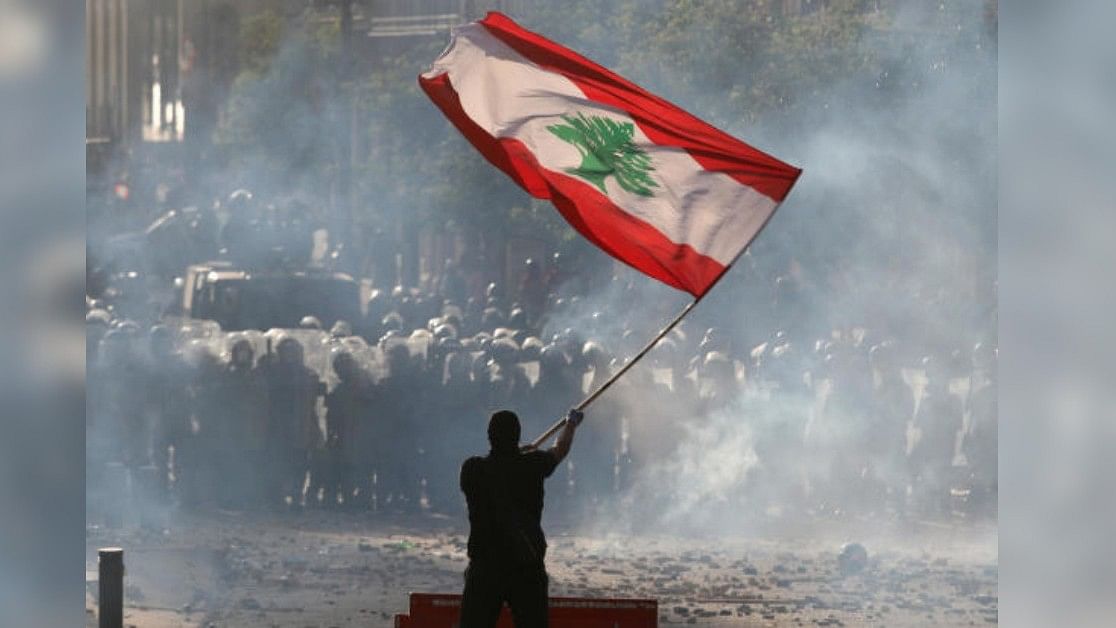 <div class="paragraphs"><p>A demonstrator waves the Lebanese flag in front of riot police during a protest in Beirut, Lebanon. </p></div>