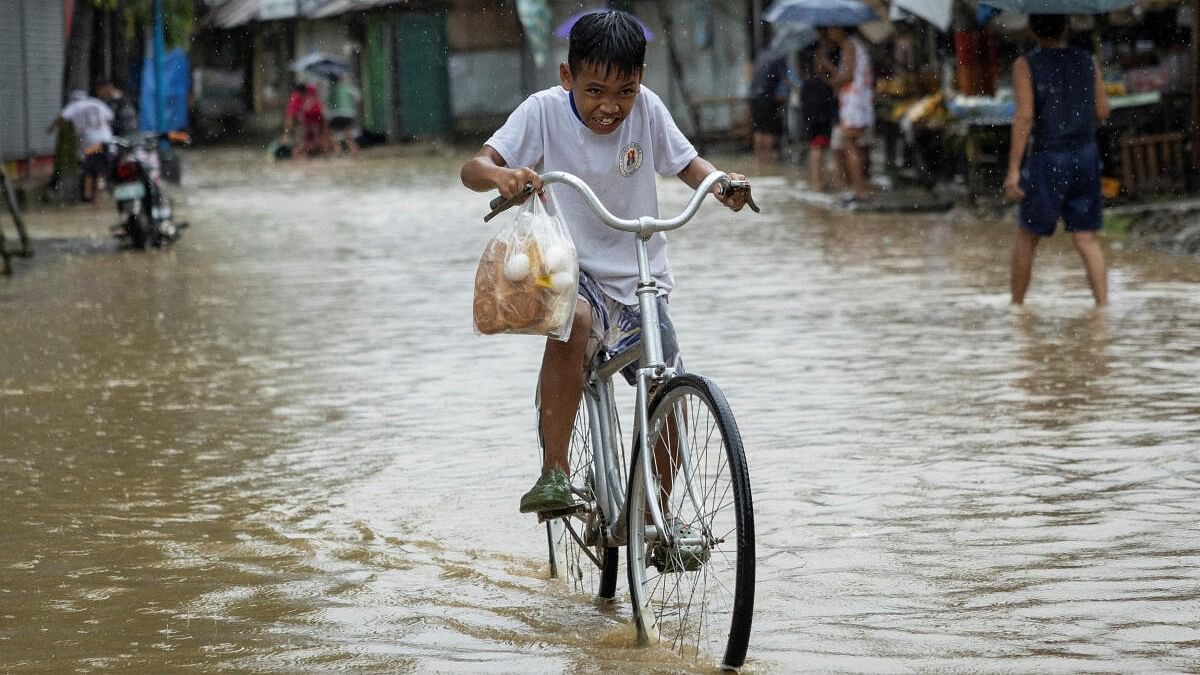 <div class="paragraphs"><p>A boy carrying a plastic bag with bread and eggs, rides his bike through a flooded road after heavy rains brought by Tropical storm Yagi, locally known as Enteng, in Baras, Rizal province, Philippines.</p></div>