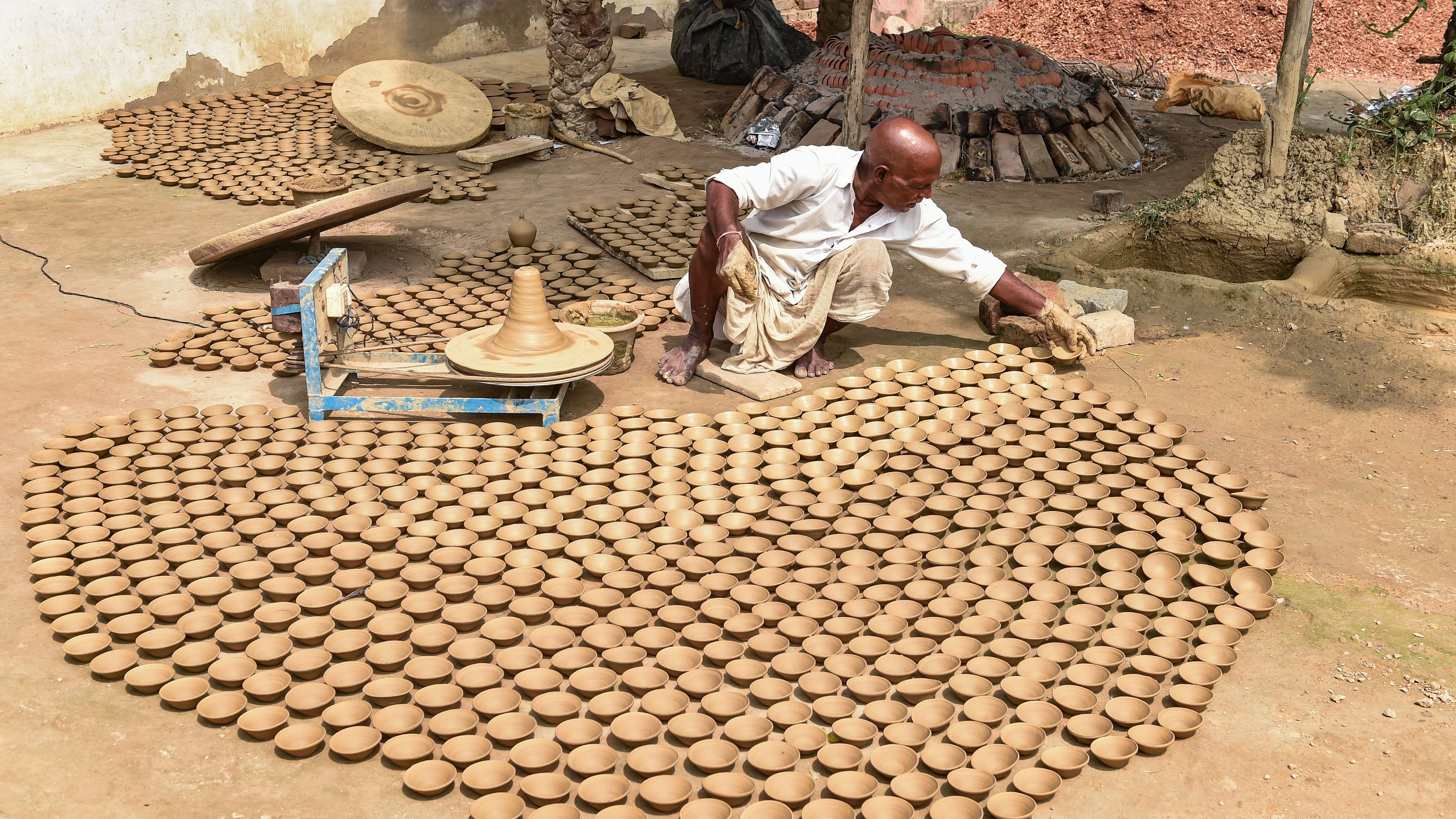 <div class="paragraphs"><p>An artist prepares earthen lamps (diyas) to be used in the 'Deepotsav' festival.</p></div>