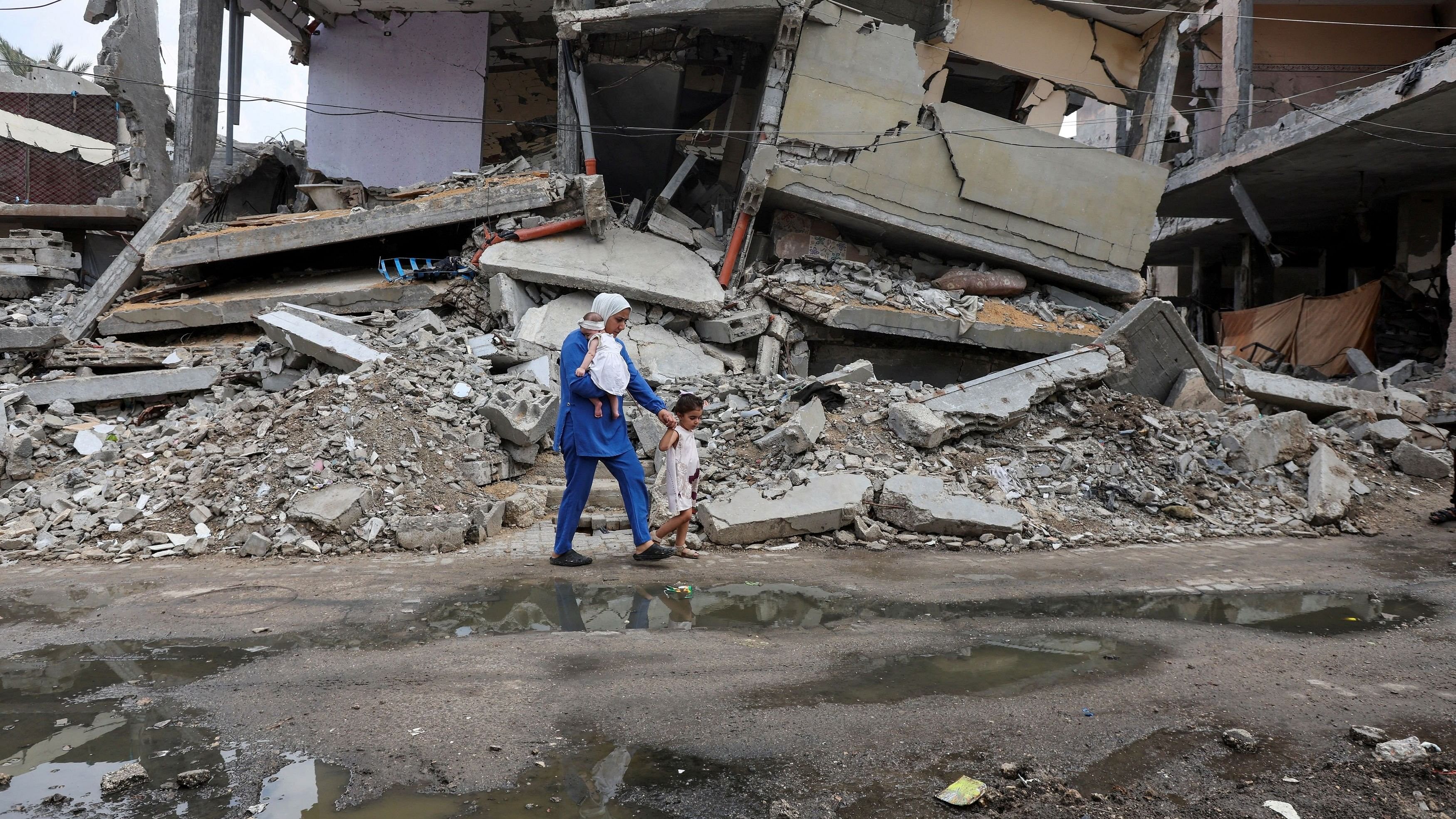 <div class="paragraphs"><p>In this fil e image, a displaced Palestinian mother, walks past the rubble of a house destroyed in an Israeli strike.</p></div>