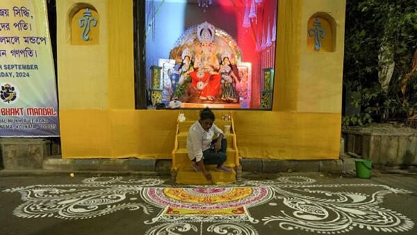 <div class="paragraphs"><p>A devotee prepares ‘Rangoli’ in front of an idol of Lord Ganesha at a pandal</p></div>