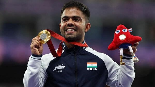 <div class="paragraphs"><p>Gold medallist Navdeep of India celebrates on the podium while holding the Paralympic mascot the Phryge</p></div>