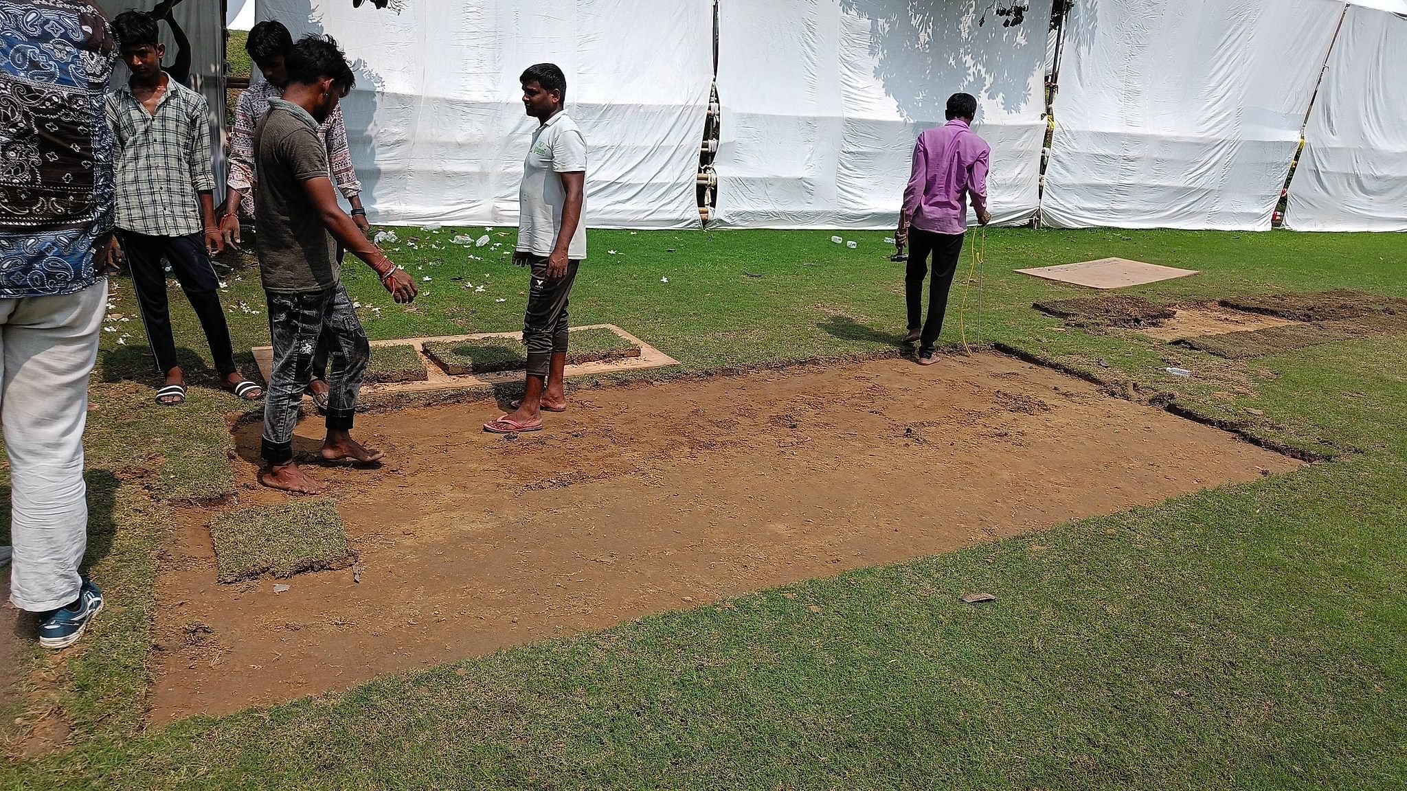 <div class="paragraphs"><p>Groundsmen cutting dry patches of grass to use on the field.</p></div>