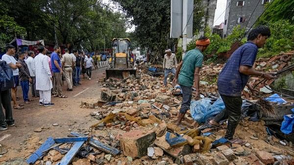 <div class="paragraphs"><p>People look on as an excavator is being used to remove the debris after a wall of a 'dargah' collapsed at Nabi Karim area, in New Delhi, Friday, Sept. 13, 2024. At least one person died and two others injured in the incident, according to officials. </p></div>