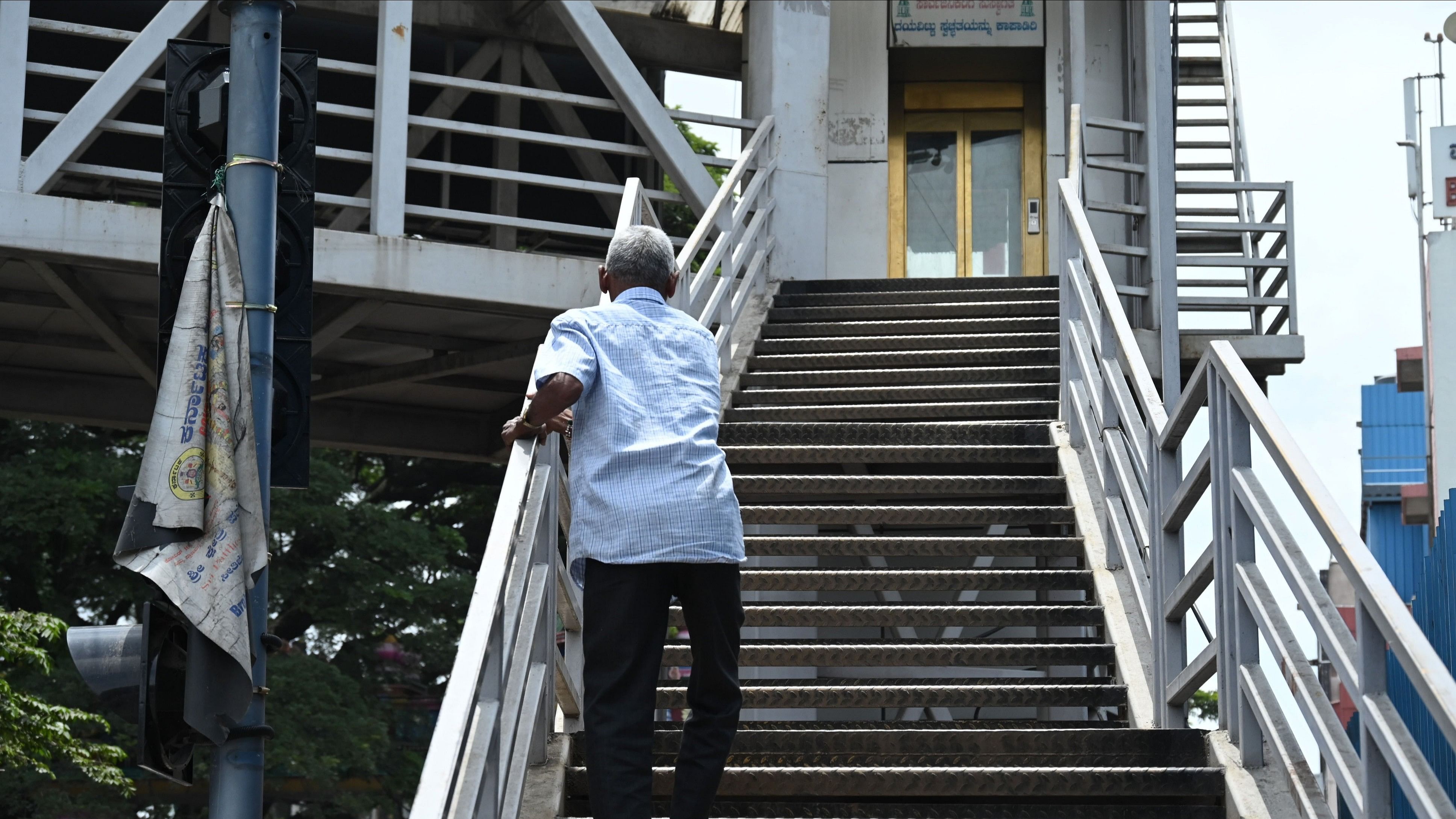 <div class="paragraphs"><p>An elderly man struggles to climb the stairs at the skywalk as the elevator lies defunct just a stone's throw away from the BBMP head office near Corporation Circle in Bengaluru. </p></div>