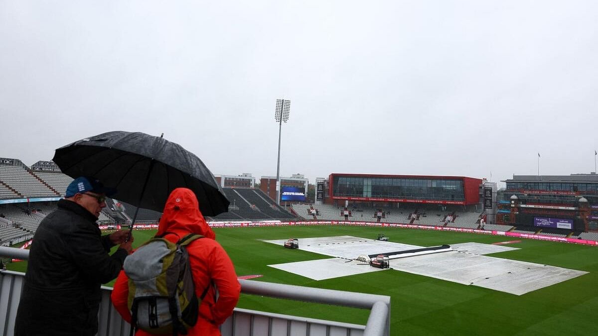 <div class="paragraphs"><p>General view as spectators shelter under an umbrella as covers are on the pitch during a rain delay.</p></div>