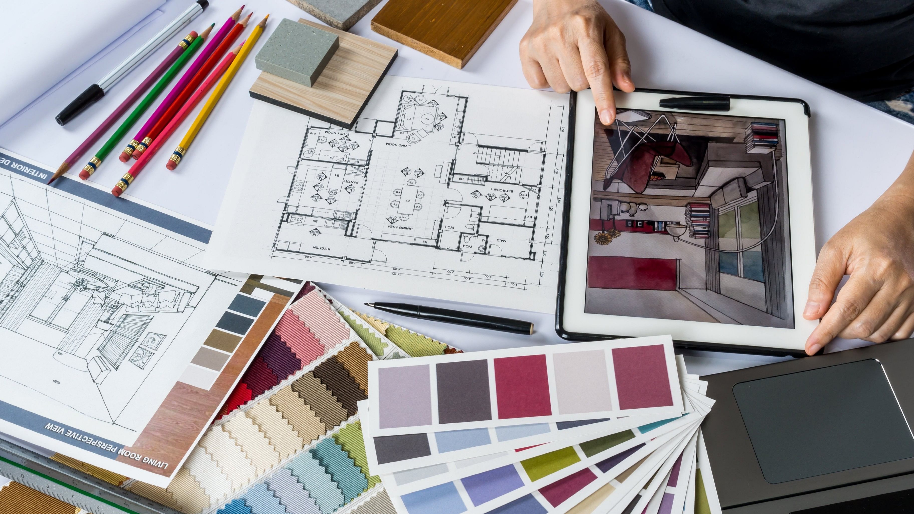 Top view of architects/ interior designer hands working with tablet computer, material sample on desk