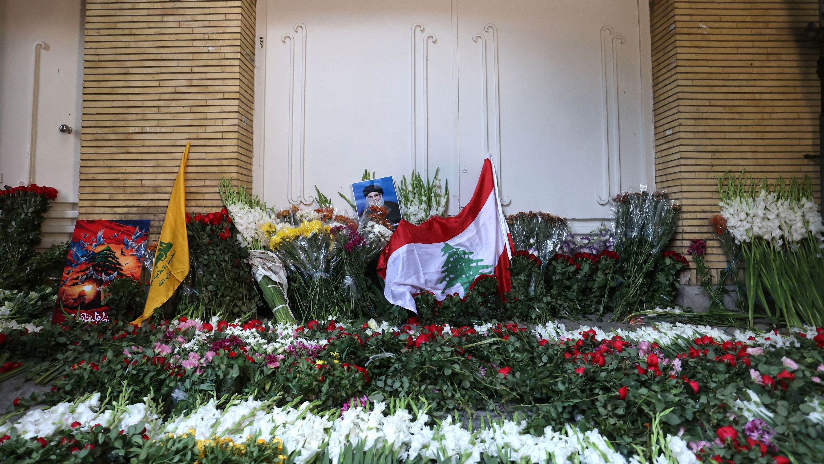 <div class="paragraphs"><p>The Lebanese Flag is displayed among the flowers at the gate of Lebanon's Embassy of Iran following the explosion of pagers across Lebanon, in Tehran, Iran September 18, 2024. </p></div>