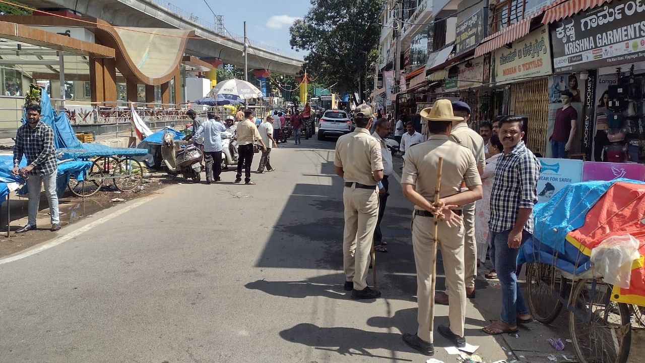 Police stand guard as the structures are bring removed on the service road in Vijayanagar. SPECIAL ARRANGEMENT 