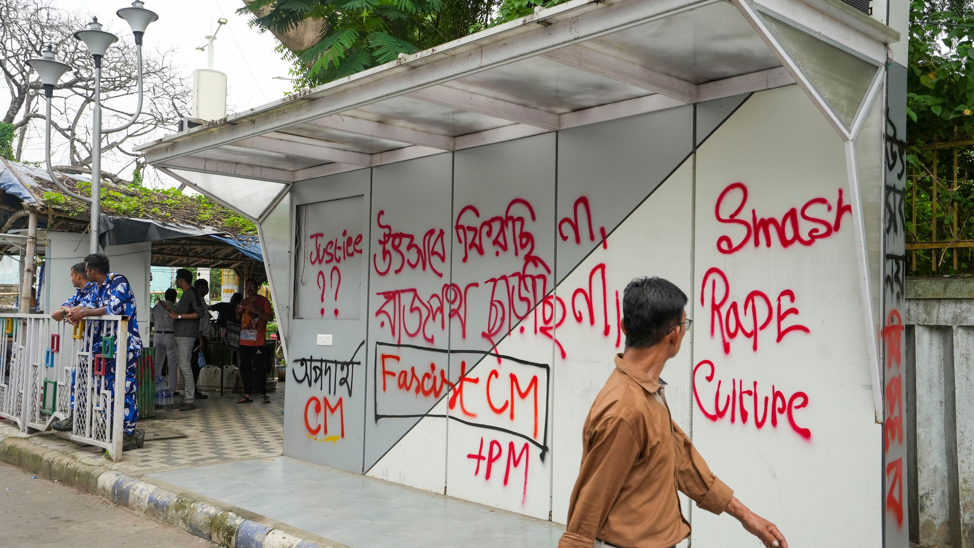 <div class="paragraphs"><p>Kolkata: A man walks past a bus stand painted with slogans on the third day of the junior doctors' dharna against the alleged rape and murder of a trainee woman doctor at the RG Kar Medical College and Hospital, near Swasthya Bhawan, in Kolkata.</p></div>