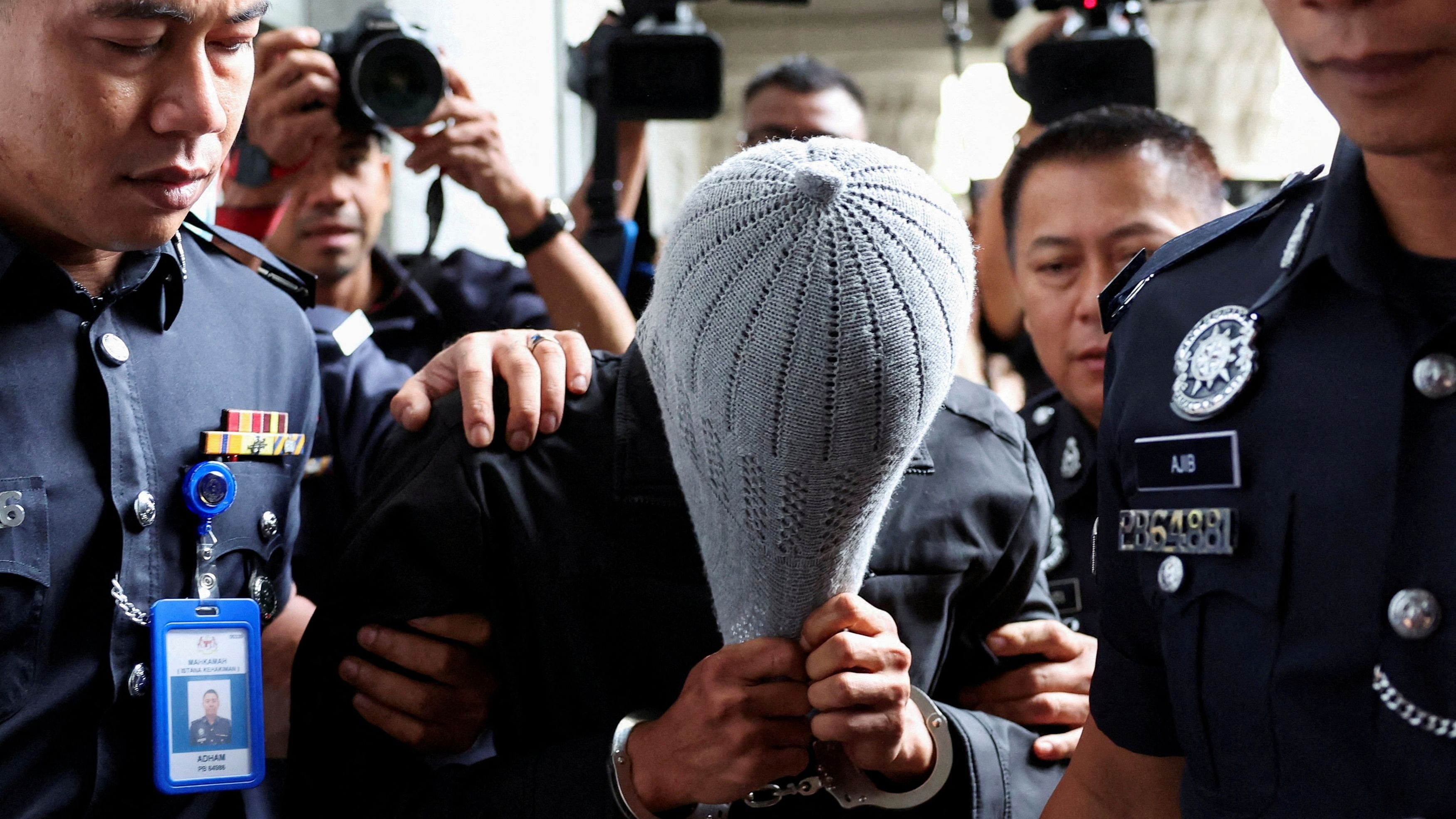 <div class="paragraphs"><p>A man linked to Global Ikhwan Service and Business Holdings (GISB) covers his face as he is escorted by police officers after being charged in a court in Putrajaya, Sept 18, 2024.</p></div>