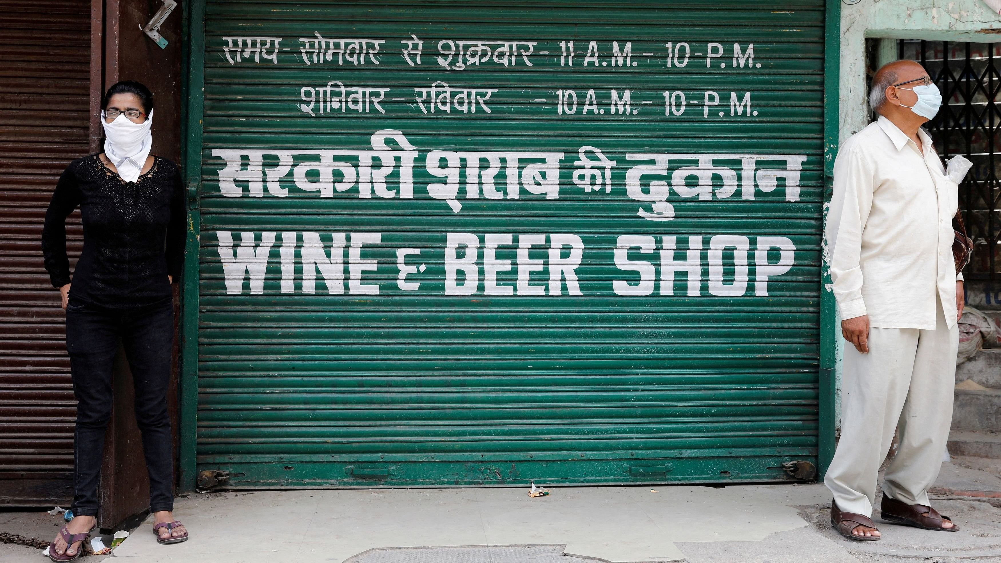 <div class="paragraphs"><p>People stand outside a wine shop to buy liquor.</p></div>