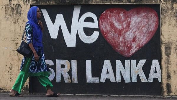 <div class="paragraphs"><p>A woman walks past graffiti on a wall along a main road, ahead of the upcoming presidential election scheduled for September 21, in Colombo, Sri Lanka.</p></div>