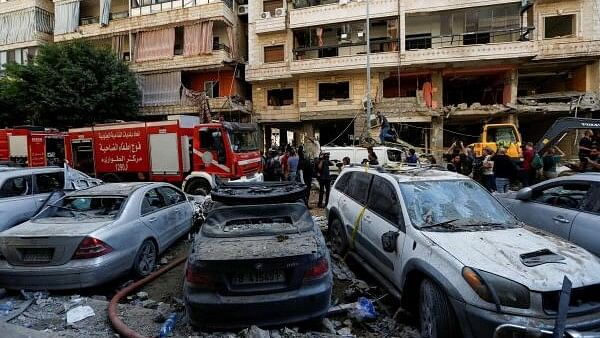 <div class="paragraphs"><p>People gather near a firetruck and damaged vehicles at the site of Friday's Israeli strike, as search and rescue operations continue, in Beirut's southern suburbs, Lebanon.&nbsp;</p></div>