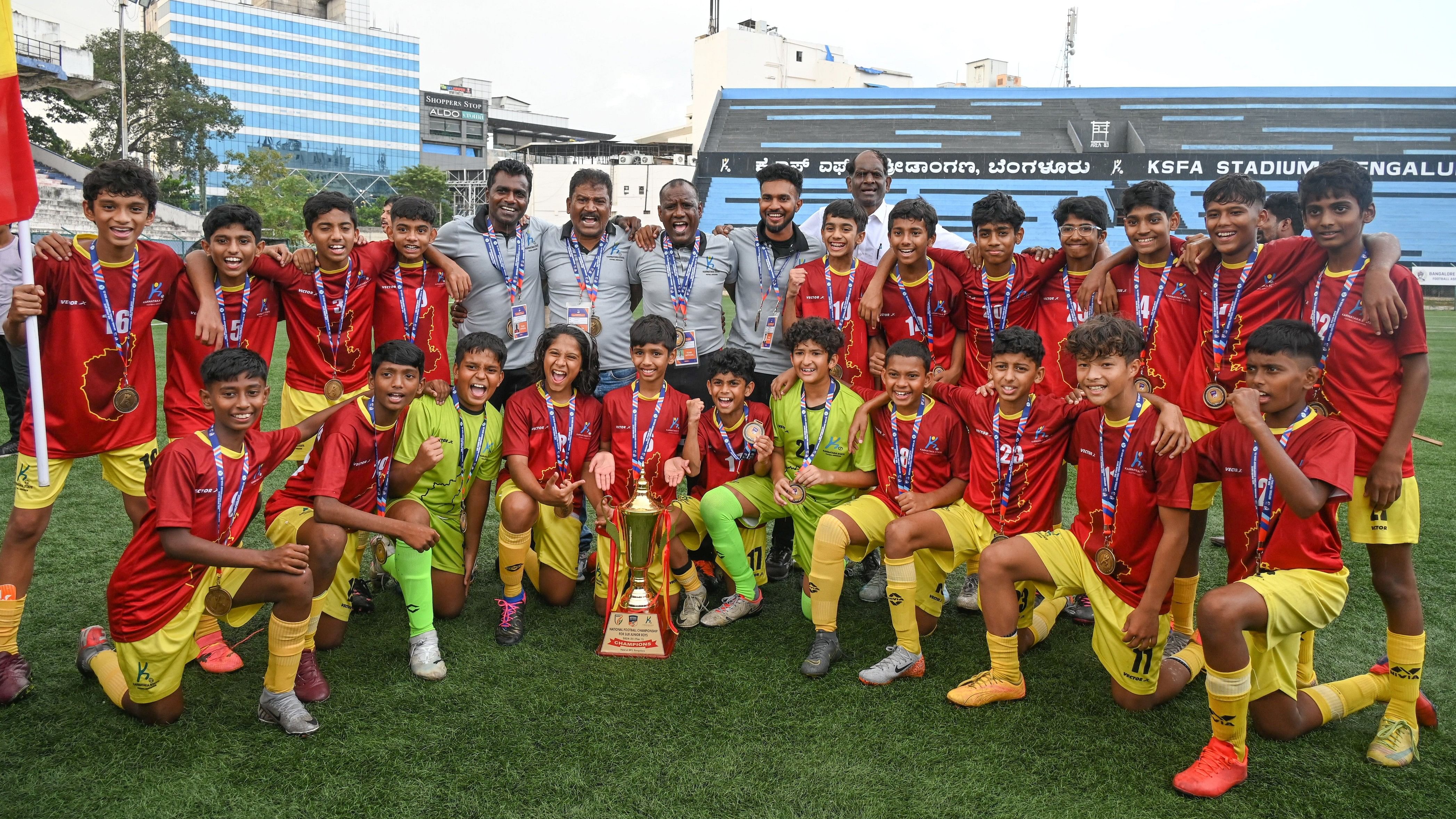 <div class="paragraphs"><p>A jubilant Karnataka football team pose with the trophy and medals after winning the Tier I Sub-junior Boys’ National Football Championship at the Bangalore Football Stadium in Bengaluru on Sunday. </p></div>