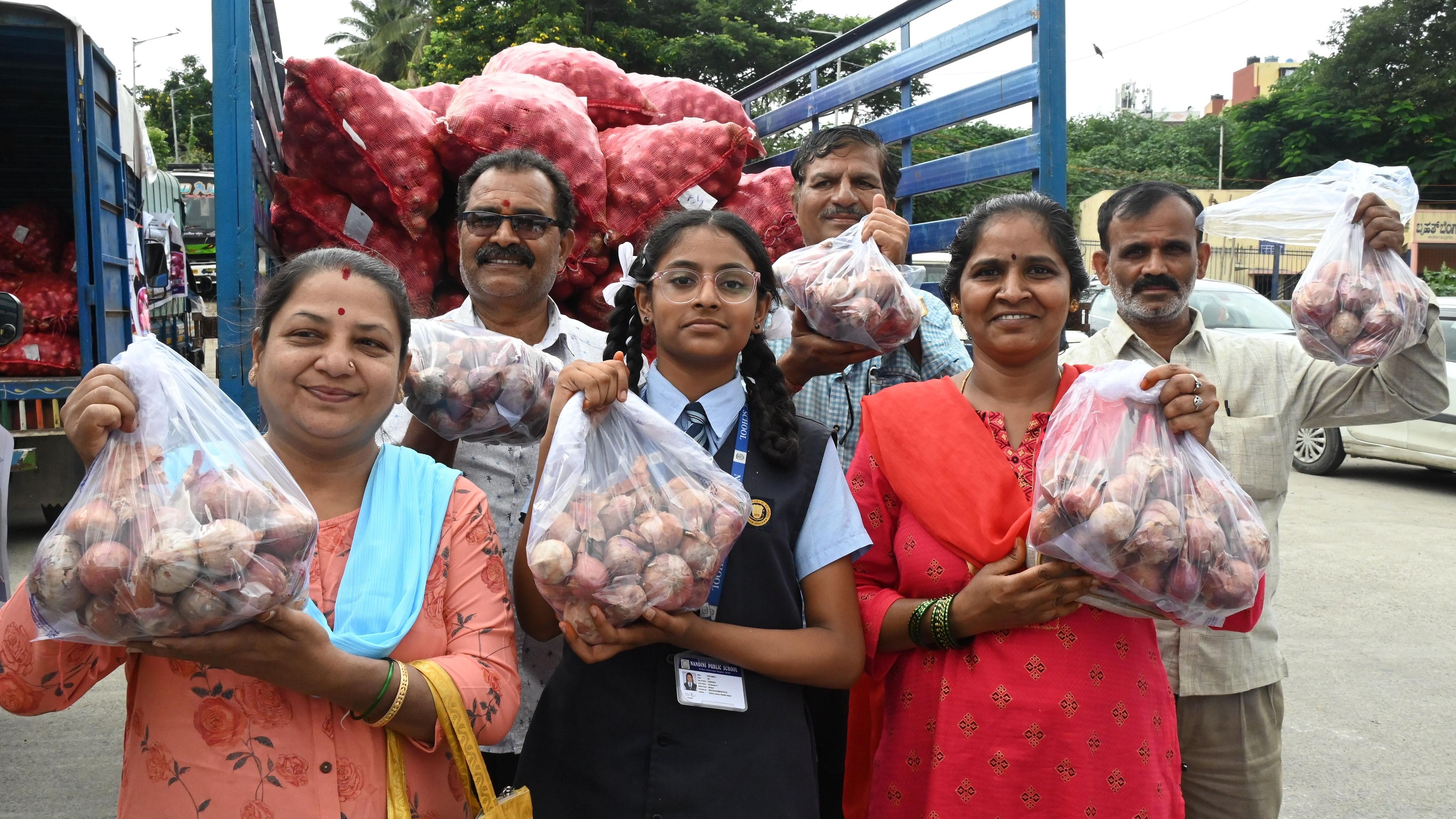 <div class="paragraphs"><p>People show pack of onion after buying it at the Rs&nbsp;35 from a mobile van at Nandini layout in Bengaluru on Monday.</p></div>