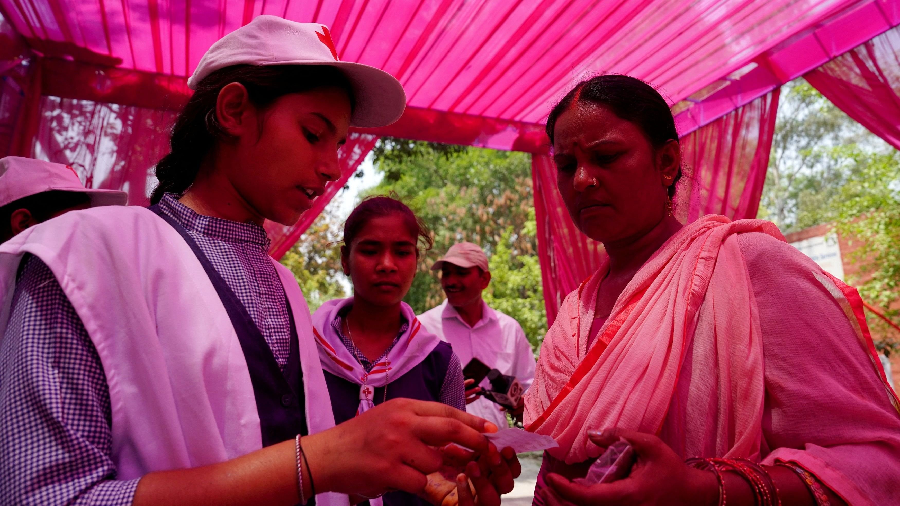 <div class="paragraphs"><p>Volunteers check the voter slip of a woman as she arrives to cast her vote outside a polling station during the sixth phase of India's general election in Karnal, in the northern state of Haryana, India</p></div>