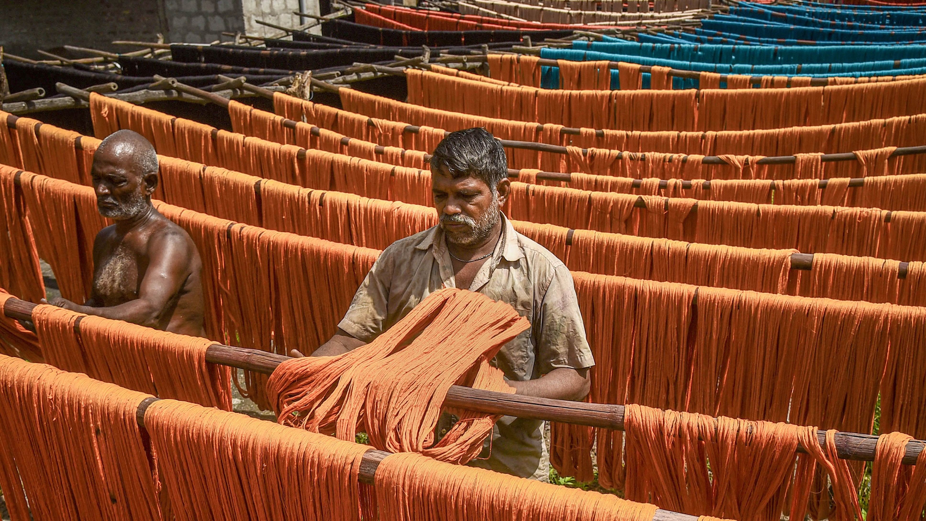 <div class="paragraphs"><p>Workers hang dyed yarn for drying under the sun as seen on the National Handloom Day at a textile mill, in Guntur district</p></div>