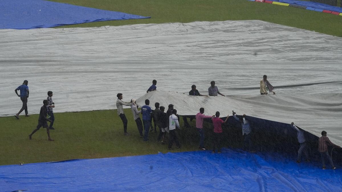 <div class="paragraphs"><p>Ground staff cover the ground during rains ahead of the 2nd test match between India and Bangladesh in Kanpur.</p></div>