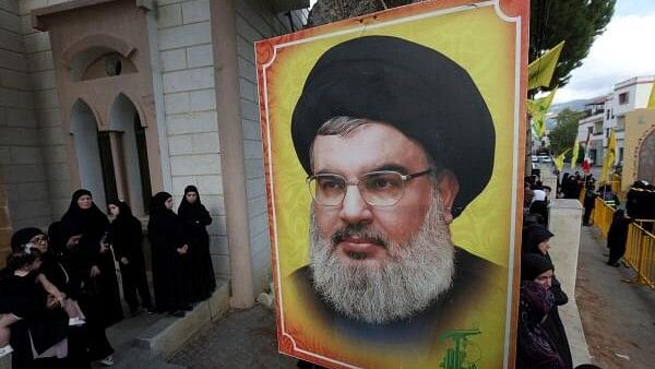 <div class="paragraphs"><p>People stand near a picture of Hezbollah leader Sayyed Hassan Nasrallah.&nbsp;</p></div>