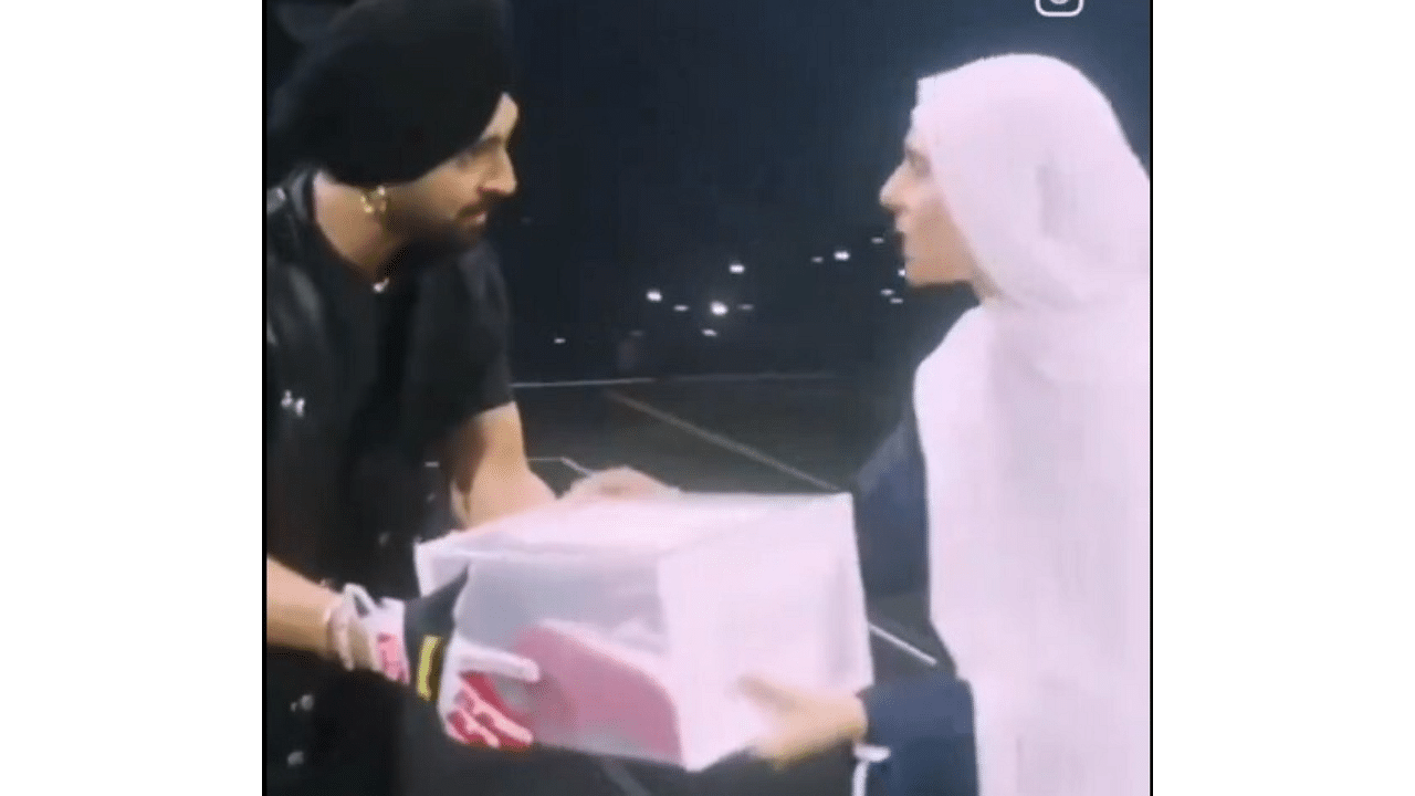 <div class="paragraphs"><p>Diljit Dosanjh presents a box with shoes to one of his fans.</p></div>