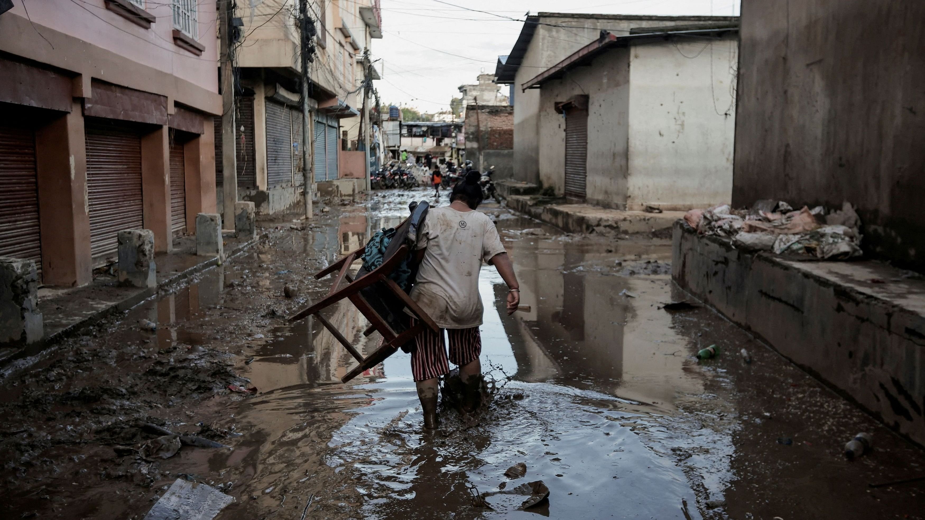 <div class="paragraphs"><p>A woman carrying a chair walks along a muddy street as the floodwater recedes from a residential area that was flooded by the overflowing Bagmati River following heavy rains in Kathmandu, Nepal.</p></div>