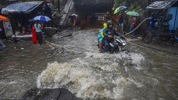 <div class="paragraphs"><p>Commuters on a waterlogged road amid rain in Mumbai.</p></div>