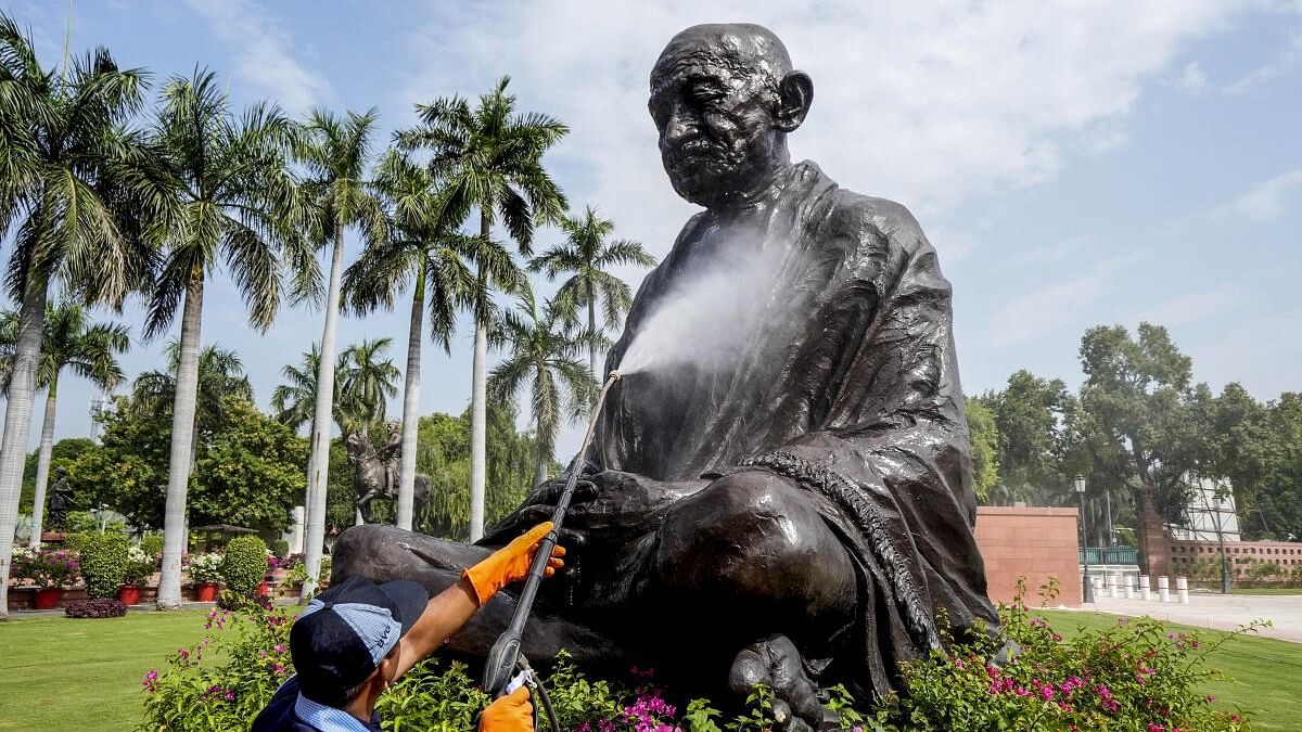 <div class="paragraphs"><p>A worker cleans a statue of Mahatma Gandhi</p></div>