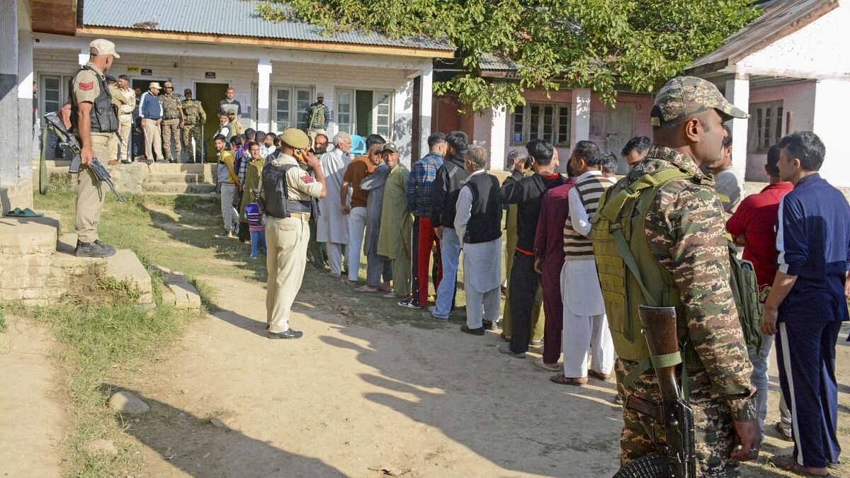 <div class="paragraphs"><p>Security personnel stand guard as voters wait in a queue to cast their votes at a polling booth during the third and final phase of Jammu &amp; Kashmir Assembly elections, at Pattan in Baramulla district, J&amp;K, Tuesday, Oct. 1, 2024.</p></div>