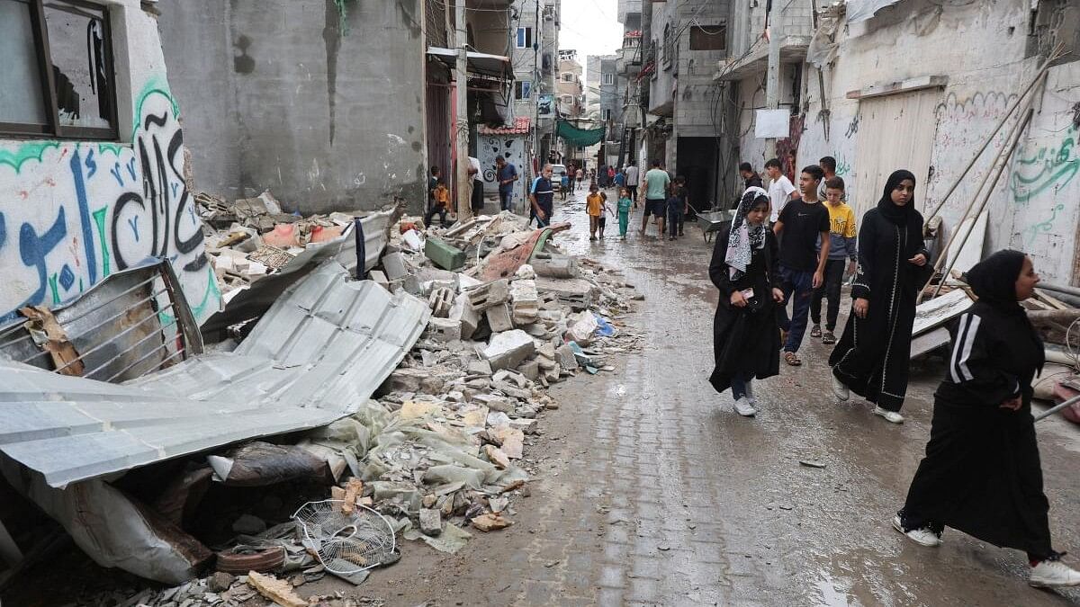 <div class="paragraphs"><p>Palestinians walk at the site of an Israeli strike on a house, amid the Israel-Hamas conflict, in Nuseirat in the central Gaza Strip.</p></div>