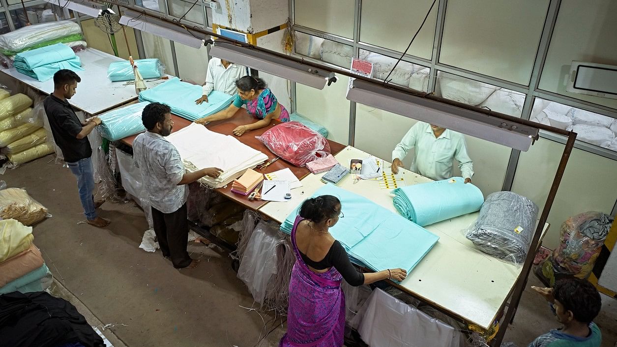 <div class="paragraphs"><p>Workers folding and wrapping textiles in plastic on floor of dyeing and printing mill.</p></div>