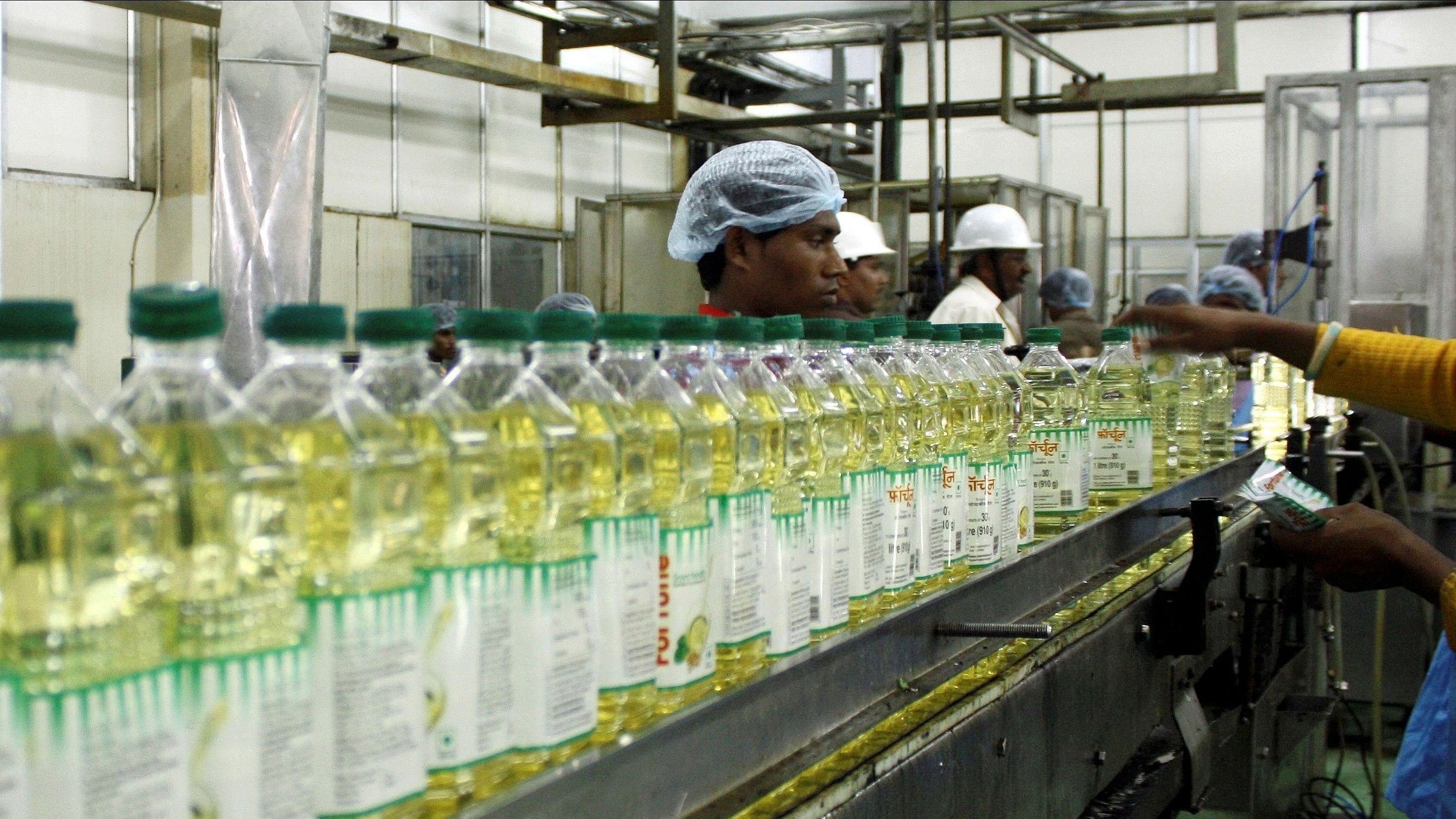 <div class="paragraphs"><p>Employees fill plastic bottles with edible oil at an oil refinery plant of Adani Wilmar Ltd. </p></div>