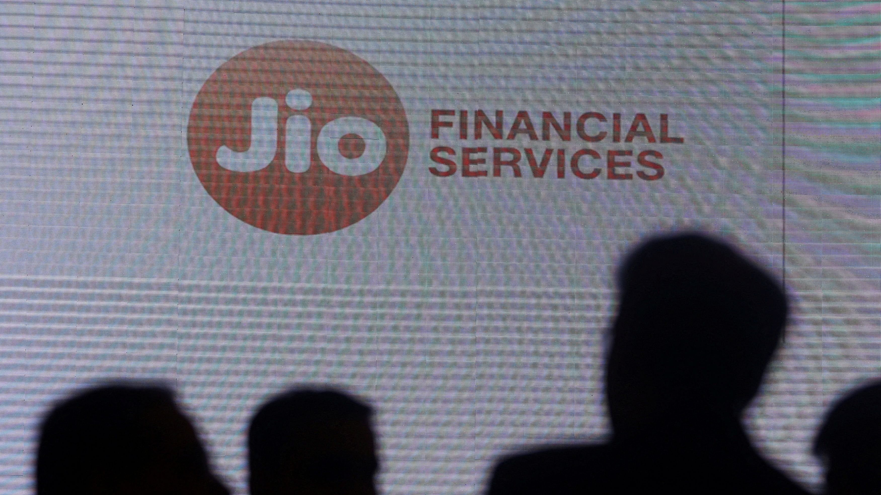 <div class="paragraphs"><p> People stand next to a logo of Jio Financial Services </p></div>