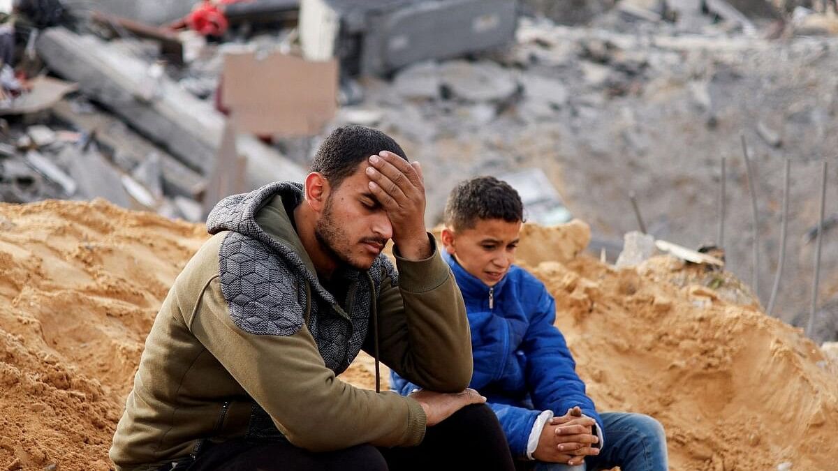 <div class="paragraphs"><p>Palestinians react as they sit at the site of an Israeli strike on a house, amid the ongoing conflict between Israel and the Palestinian Islamist group Hamas, in Rafah in the southern Gaza Strip.</p></div>