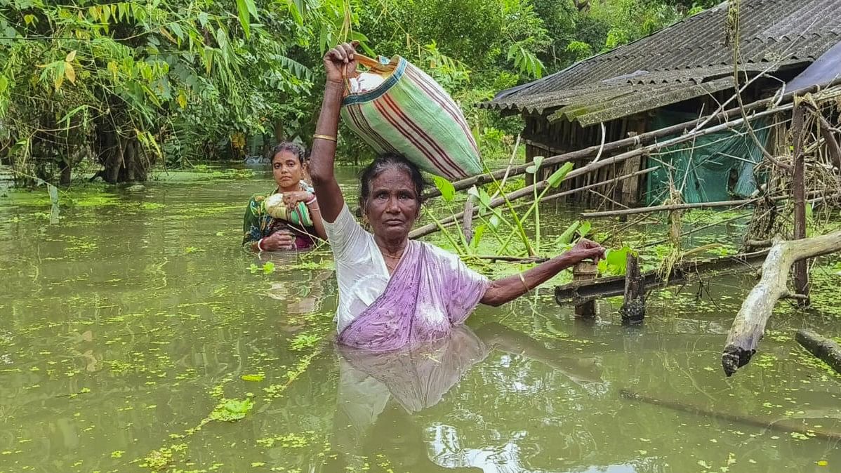 <div class="paragraphs"><p>Women carry their belongings through a flooded area, in West Medinipur district of West Bengal.</p></div>