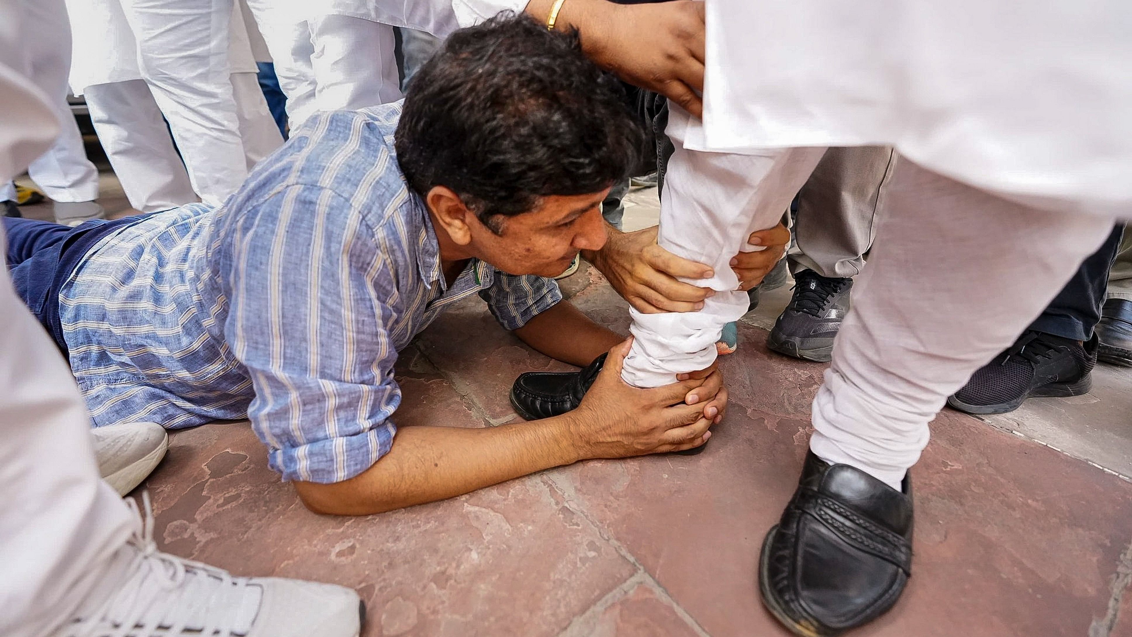 <div class="paragraphs"><p>Delhi Minister Saurabh Bharadwaj with other MLAs holds a foot of BJP MLA Vijender Gupta, asking his support for the reinstatement of bus marshals, in New Delhi.</p></div>