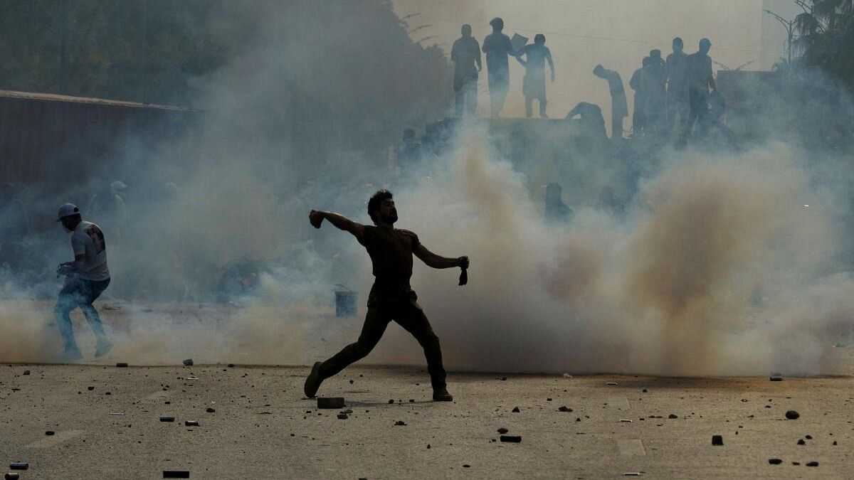 <div class="paragraphs"><p>A supporter of jailed former Pakistani PM Imran Khan's party throws back a tear gas shell during an anti-government rally in Islamabad.</p></div>