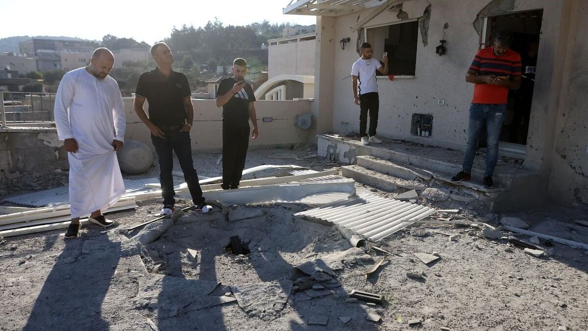 <div class="paragraphs"><p>People look at the damage to a home following a rocket attack.</p></div>