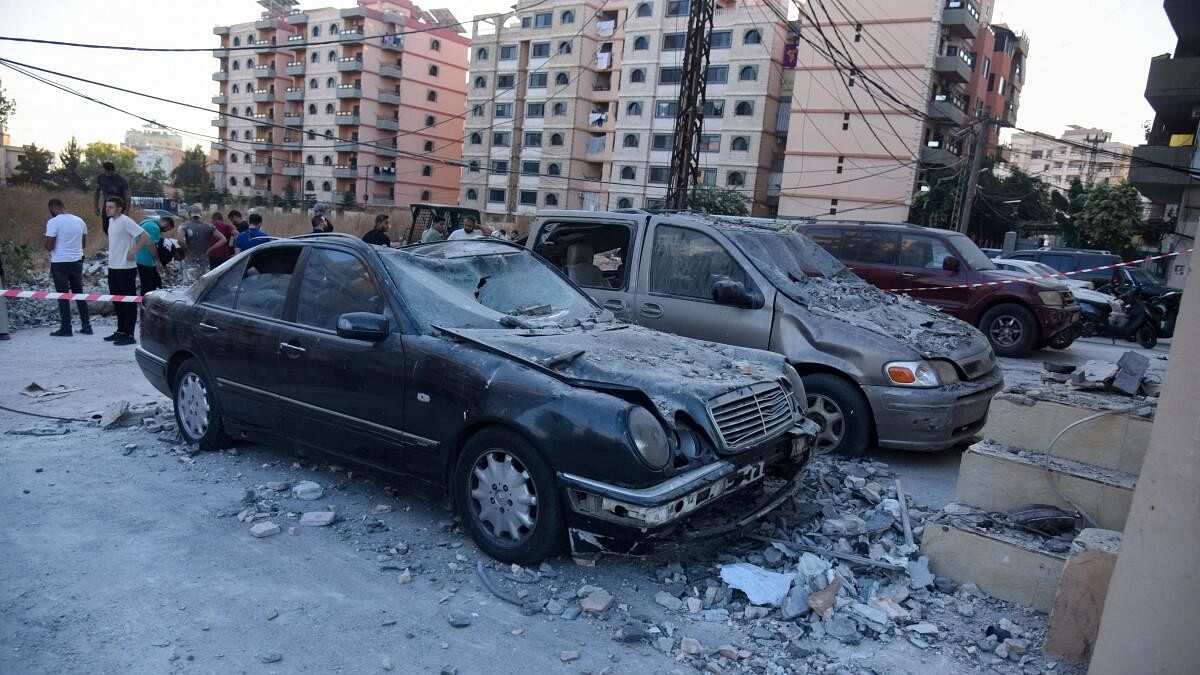 <div class="paragraphs"><p>People stand at the site hit by an Israeli strike in the northern Lebanese city of Tripoli.</p></div>