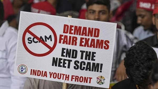 <div class="paragraphs"><p>An agitator holds a placard during a protest of the India Youth Front, an umbrella group representing I.N.D.I.A bloc parties' youth wings, over the alleged irregularities in NEET 2024 results, at Jantar Mantar, in New Delhi in July, 2024. </p></div>