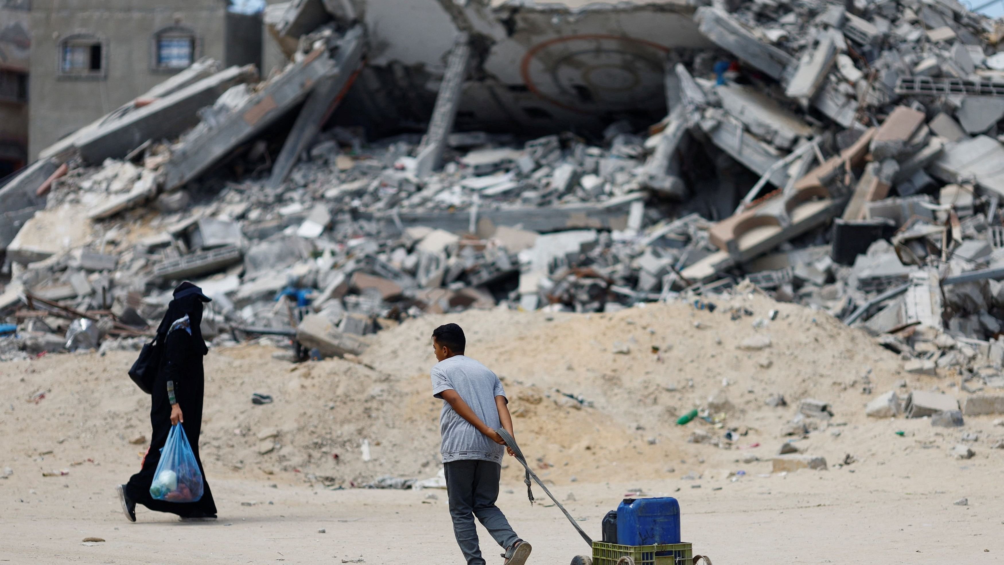 <div class="paragraphs"><p>A Palestinian boy pulls a small cart past the rubble of houses destroyed in Israel's military offensive, amid the ongoing conflict between Israel and Hamas.</p></div>