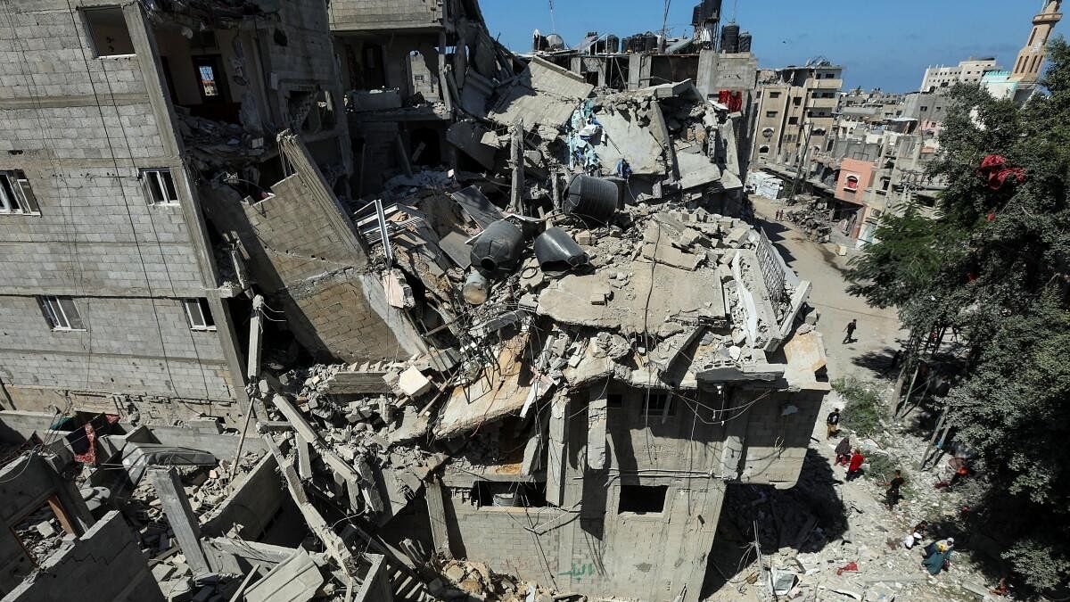 <div class="paragraphs"><p>Palestinians walk past a house hit in an Israeli strike, amid the Israel-Hamas conflict, in Bureij refugee camp, in the central Gaza Strip</p></div>