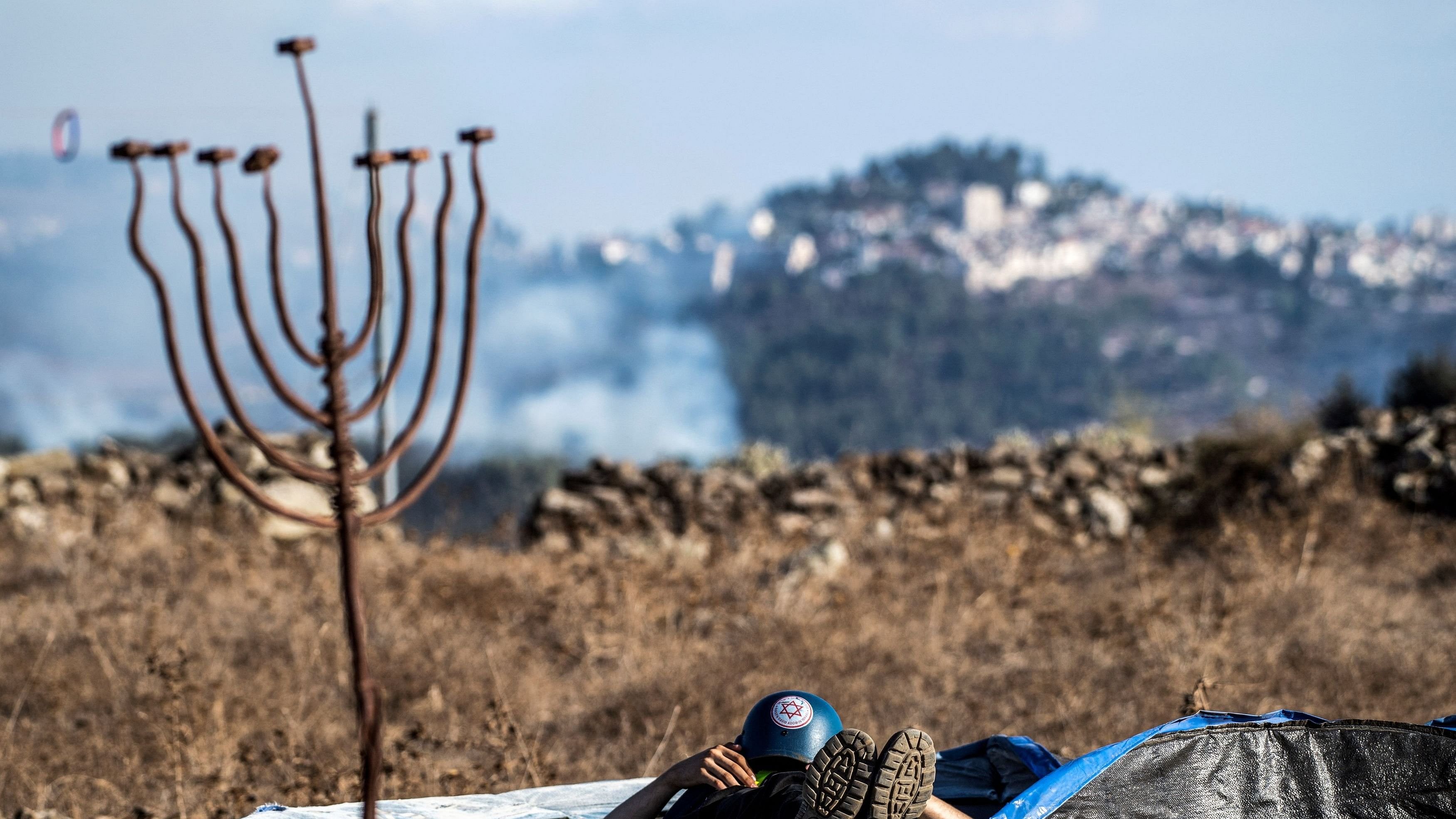 <div class="paragraphs"><p>A medical rescue personal rests on a trampoline where smoke following rockets fired from Lebanon towards Israel, seen in the background, amid cross-border hostilities between&nbsp;Hezbollah&nbsp;and Israel, in northern Israel September 21, 2024. </p></div>