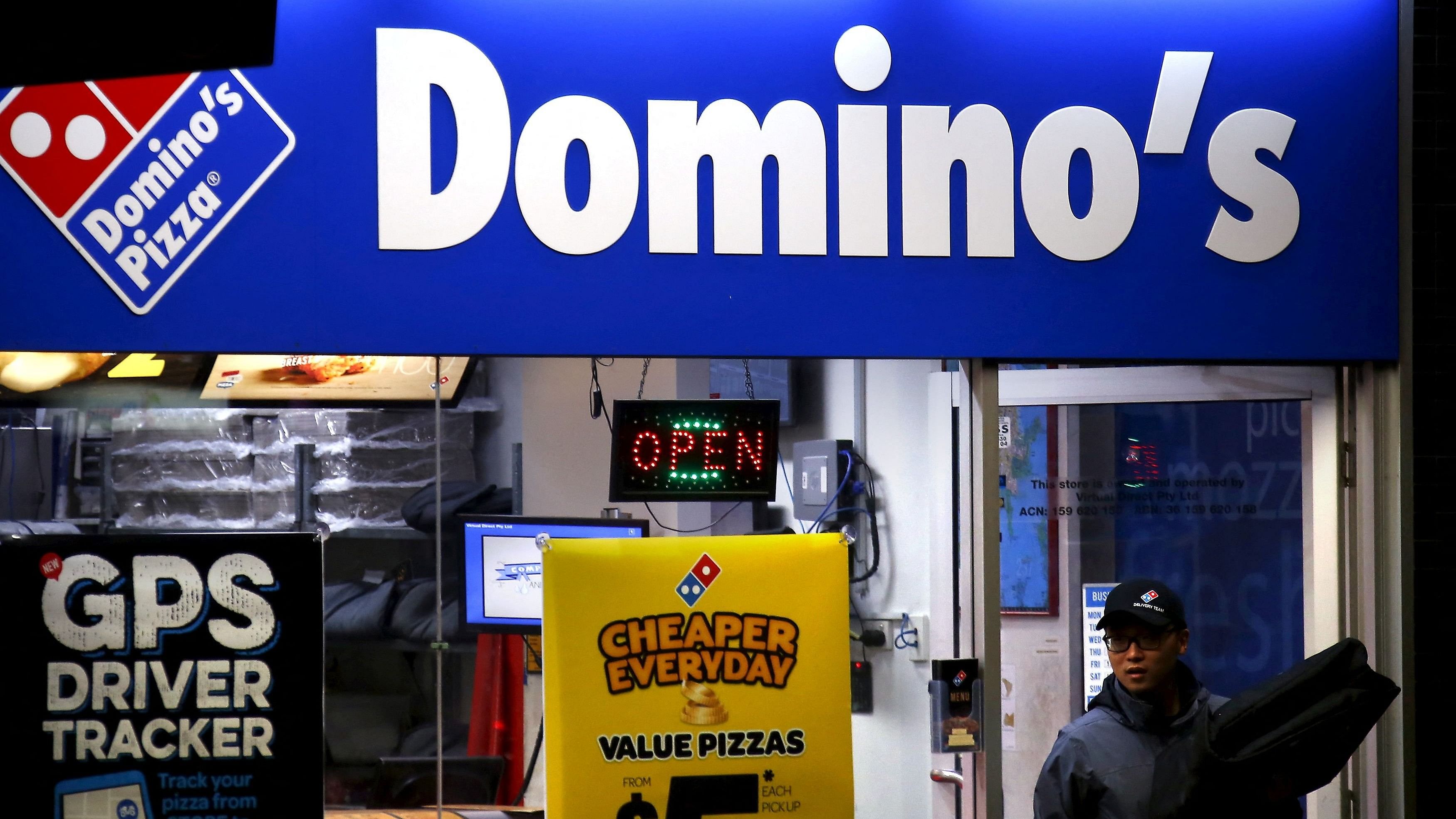 <div class="paragraphs"><p>A worker carries a pizza for delivery as he exits a Domino's pizza store.</p></div>