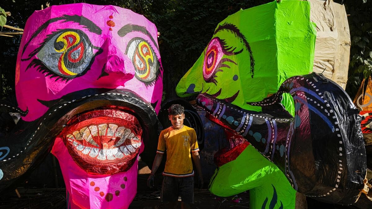 <div class="paragraphs"><p> A man poses for photos in the backfrop of effigies of demon King Ravana on the eve of Dussehra festival, in west Delhi’s Titarpur.</p></div>